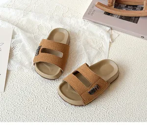 Close-up view of kids' tan suede-style sandals with stylish metal logo and double straps