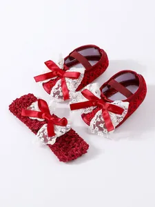Detailed view of red lace baby shoes and matching bow headband set for newborn girl