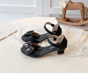 Dettaglio di scarpe da principessa nere per bambine con fiocco di paillettes