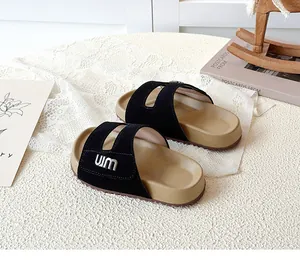 Detail view of children dual-strap slides featuring black suede and metal logo