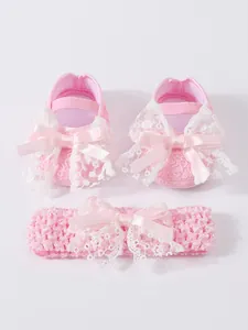 Detail view of pink newborn shoes and matching lace headband set with satin bows