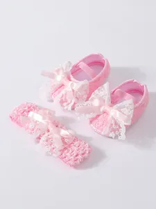 Detailed view of pink lace baby shoes and matching bow headband set for newborns