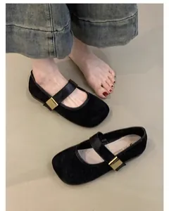 Detalle de zapatos planos Mary Jane de ante negro con una elegante hebilla dorada