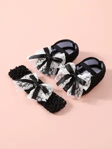 Detailed view of black lace newborn shoes and matching bow headband set for girls