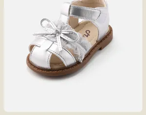 Detailed view of silver toddler girl sandals featuring lace trim and a sweet bow design