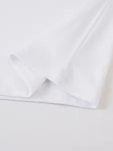Gros plan sur l'ourlet d'un t-shirt blanc montrant des finitions de couture de qualité.