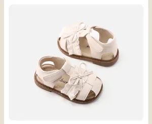 Detail view of off-white baby girl sandals with delicate lace trim and sweet bow accents