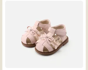Close-up of pink baby walking sandals with decorative lace bow and hollow toe design