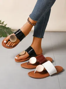 Close-up of stylish women's thong sandals featuring large metal disks and croc texture