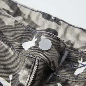 Macro close-up detail of camouflage cargo shorts showing metal button and zipper fly.