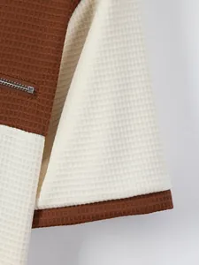 Detailed view of the waffle knit fabric and functional zipper pocket on color-block top