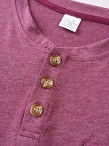 Détail en gros plan d'un t-shirt Henley bordeaux avec boutons marron et étiquette