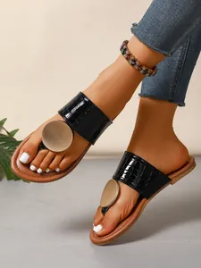Close-up of women's black crocodile leather sandals with gold metal disc ornament