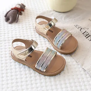 Detailed view of gold girl's flat sandals with gradient glitter straps and soft soles.