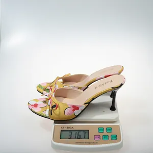 Detailed view of floral yellow high-heeled mule sandals with bow weighing 316.7g on a scale