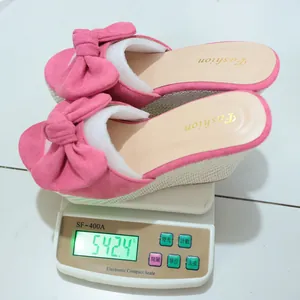 Detalle de las sandalias de cuña con lazo rosa en una báscula que pesa 542,4 gramos
