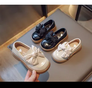 Détail de mocassins britanniques pour filles en noir et crème avec nœuds élégants