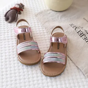 Close-up of pink metallic girls' sandals with rainbow glitter straps and soft soles.