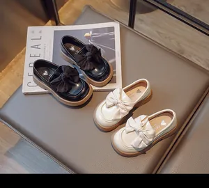 Vue détaillée de deux paires de mocassins britanniques pour enfants avec nœuds en noir et crème