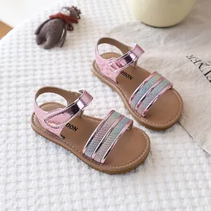 Detail of pink metallic girls' sandals featuring glitter straps and soft brown soles