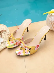 Close-up of yellow floral high heel mules with elegant bow and slim heel design