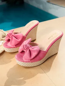 Detalle de sandalias con cuña rosa, lazo decorativo y suela con textura trenzada rústica