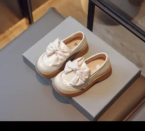 Vue détaillée des mocassins en cuir verni crème pour filles avec un grand nœud