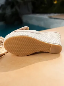 Detalle de sandalias de cuña beige con suela de paja tejida y base de goma