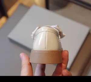Gros plan du talon de mocassins en cuir verni blanc pour filles avec semelle marron