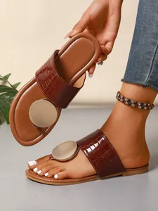 Macro view of stylish brown croc-pattern thong sandals with metallic gold disc detail