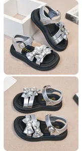 Detailed view of girls' silver sandals with rhinestone bows and metallic finish