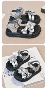 Detail showing the rhinestone bow and metallic silver finish of the girl's sandals.