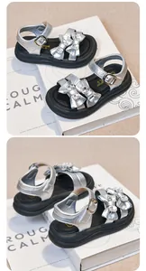 Close-up of silver girl's sandals featuring rhinestone bows and black platform soles