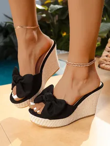 Vista detallada de sandalias de cuña con lazo negro y plataforma de paja trenzada