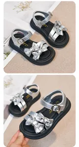 Close-up detail of silver girl's sandals featuring sparkly rhinestone bow accents