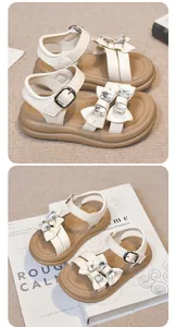Detail view of girl's cream sandals featuring rhinestone bows and adjustable ankle straps.