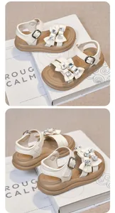 Close-up of girls' white sandals with rhinestone bow details and thick tan soles