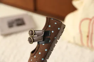 Detailopname van bruine Mary Jane-meisjesschoenen met blauwe stippen en dubbele gespen