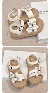 Detailed view of cream girls' sandals featuring rhinestone bow accents and buckle strap