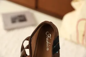 Detailopname van bruine suède kinderschoenen met zilveren Fashion-logo