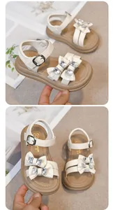 Close-up detail view of white girls' sandals with sparkling rhinestones and bow accents
