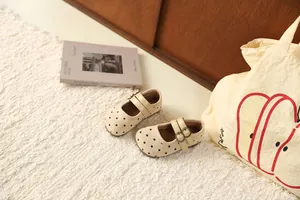 Detailopname van schattige beige polka dot Mary Jane schoenen voor meisjes op een tapijt