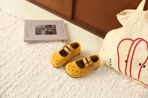 Schattige gele polka dot Mary Jane schoenen voor meisjes op een zacht wit tapijt