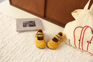 Detailopname van schattige gele polkadots Mary Janes voor meisjes op een zacht tapijt