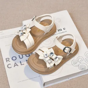 Elegant white girls' sandals featuring rhinestone bows and durable brown non-slip soles.