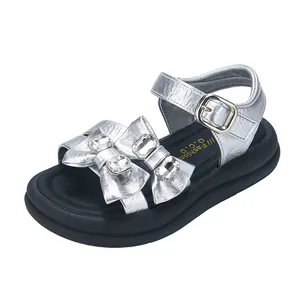 Shiny silver girl's sandals featuring rhinestone bow accents and a thick black sole