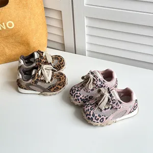 Primo piano di sneakers in mesh per bambini con stampa leopardata marrone e rosa.
