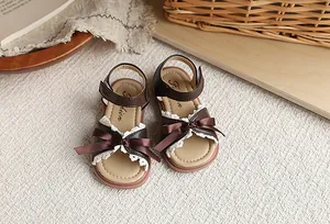 Détail de sandales marron pour fille avec nœud en ruban et dentelle