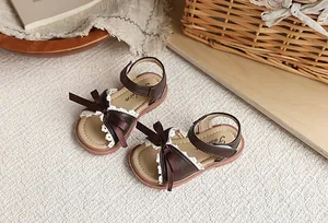 Vue détaillée de sandales marron pour filles avec dentelle blanche et nœud élégant