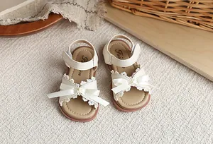 Détail rapproché de sandales princesse crème pour filles avec nœud et dentelle